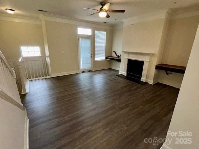 unfurnished living room with dark hardwood / wood-style flooring, ornamental molding, and a healthy amount of sunlight