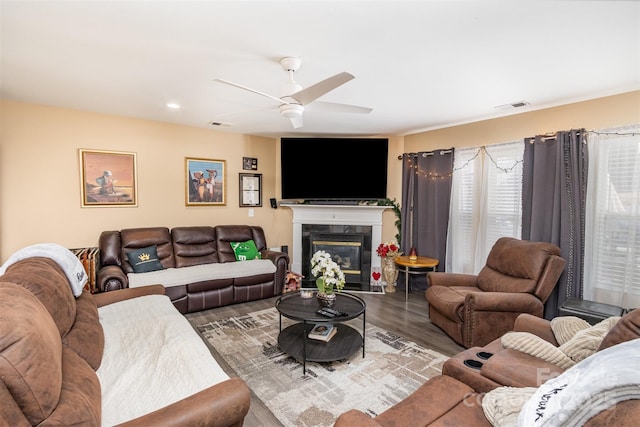 living room with ceiling fan, wood-type flooring, and a high end fireplace