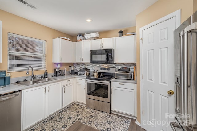 kitchen with decorative backsplash, appliances with stainless steel finishes, white cabinetry, and sink