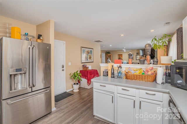 kitchen with high quality fridge, white cabinetry, kitchen peninsula, and light wood-type flooring