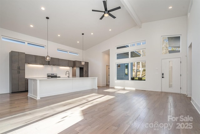 unfurnished living room with beamed ceiling, light hardwood / wood-style floors, high vaulted ceiling, and ceiling fan