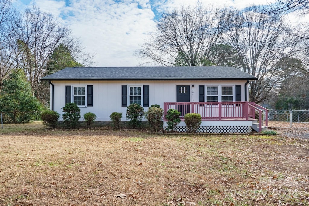 ranch-style house featuring a front yard and a wooden deck