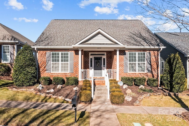 view of front of home with a shingled roof and brick siding