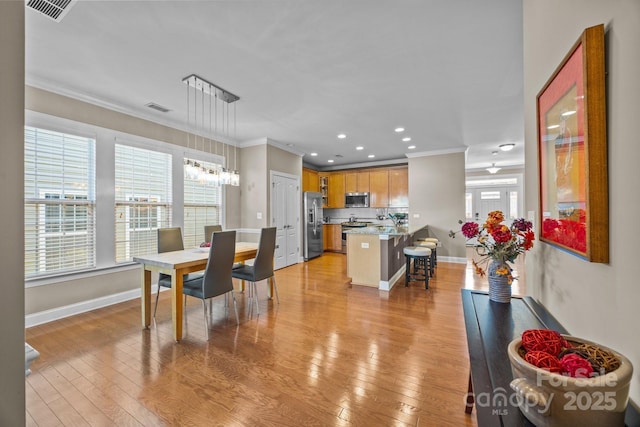 dining room with light wood-type flooring and crown molding