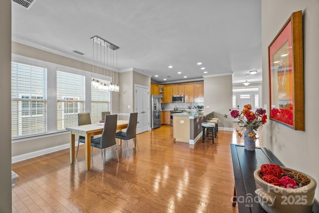 dining space featuring crown molding and light hardwood / wood-style flooring