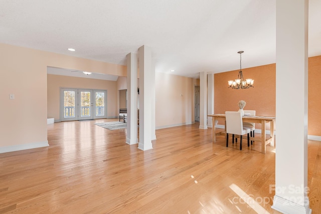 living room featuring a notable chandelier, light hardwood / wood-style flooring, and french doors