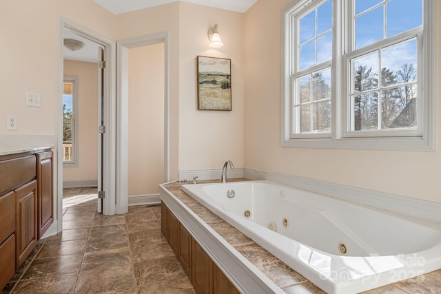 bathroom featuring a relaxing tiled tub and vanity