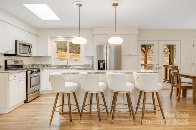 53 Jump Cove Rd, Weaverville, NC 28787 - kitchen with appliances with stainless steel finishes, a skylight, white cabinets, and a kitchen bar