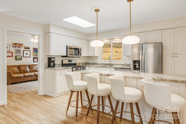 53 Jump Cove Rd, Weaverville, NC 28787 - kitchen with appliances with stainless steel finishes, a skylight, a breakfast bar area, and light wood-type flooring