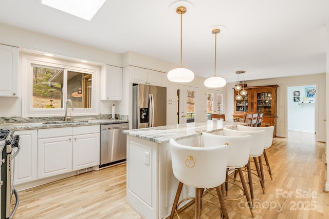 53 Jump Cove Rd, Weaverville, NC 28787 - kitchen with stainless steel appliances, light wood-type flooring, a center island, a kitchen bar, and light stone countertops