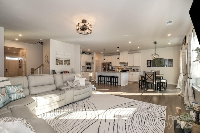 living room with dark wood-type flooring and a notable chandelier