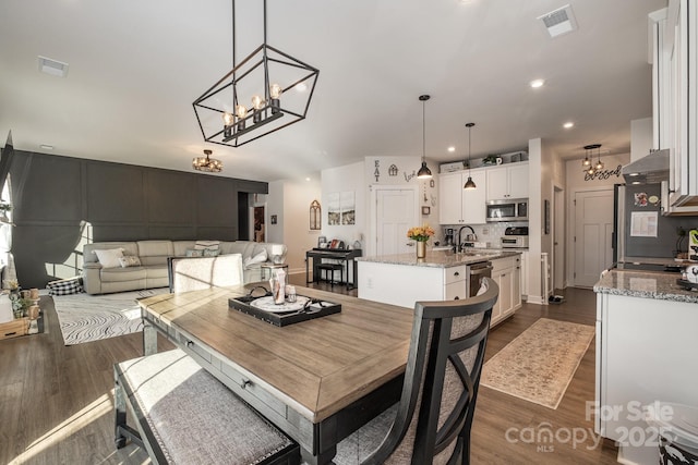 dining room with an inviting chandelier, dark wood-type flooring, and sink