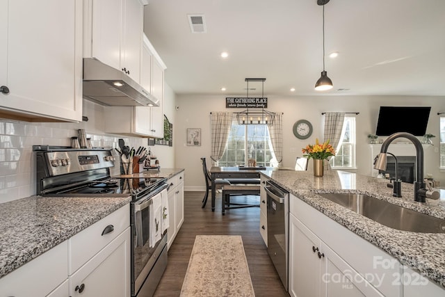 kitchen featuring white cabinets, sink, hanging light fixtures, light stone countertops, and stainless steel appliances