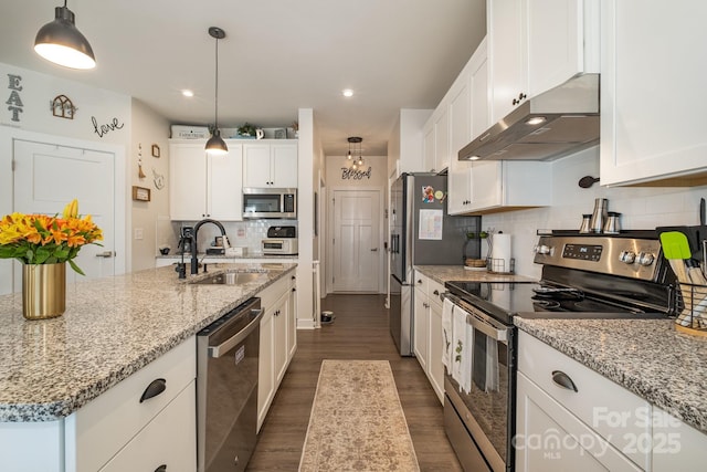 kitchen featuring pendant lighting, a kitchen island with sink, decorative backsplash, appliances with stainless steel finishes, and white cabinetry