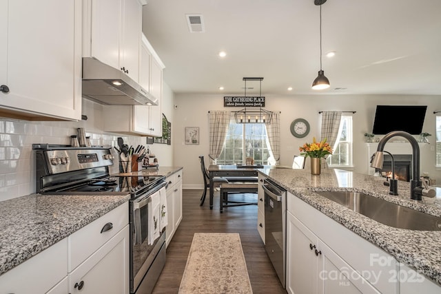 kitchen featuring light stone countertops, white cabinetry, sink, hanging light fixtures, and appliances with stainless steel finishes