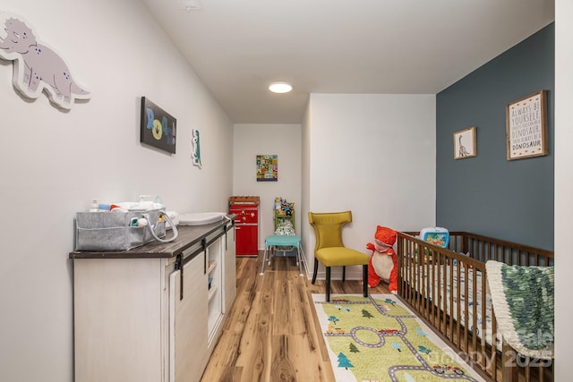 bedroom featuring a nursery area and light hardwood / wood-style floors