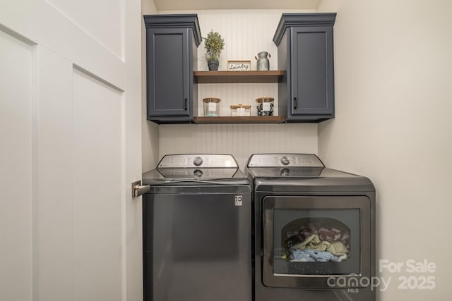 clothes washing area with washing machine and clothes dryer and cabinets