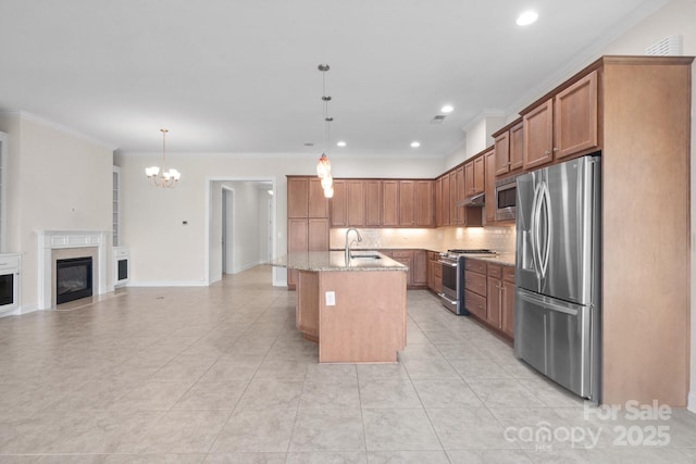 kitchen featuring brown cabinetry, an island with sink, open floor plan, stainless steel appliances, and pendant lighting