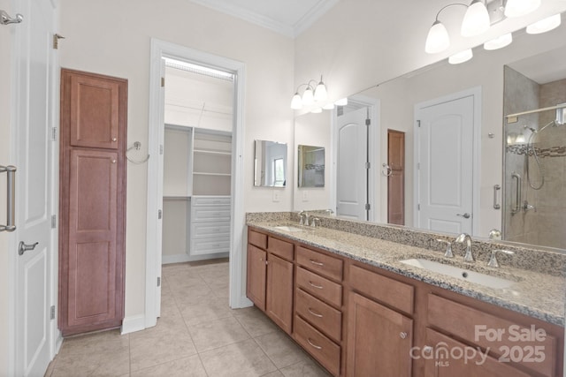 bathroom featuring a shower stall, ornamental molding, a walk in closet, and a sink