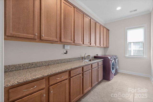 clothes washing area featuring cabinet space, ornamental molding, a sink, separate washer and dryer, and baseboards