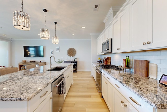 kitchen featuring white cabinets, stainless steel appliances, a kitchen island with sink, and sink