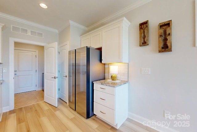 kitchen with stainless steel fridge, light wood-type flooring, ornamental molding, tasteful backsplash, and white cabinetry