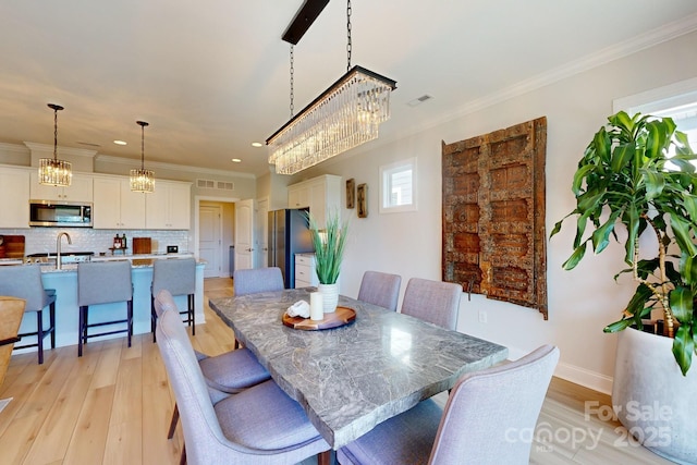 dining area featuring crown molding, sink, and light hardwood / wood-style floors