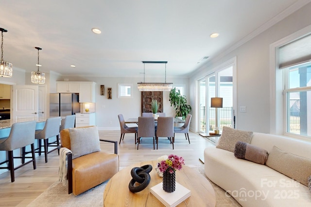 living room with light hardwood / wood-style floors, a notable chandelier, and ornamental molding