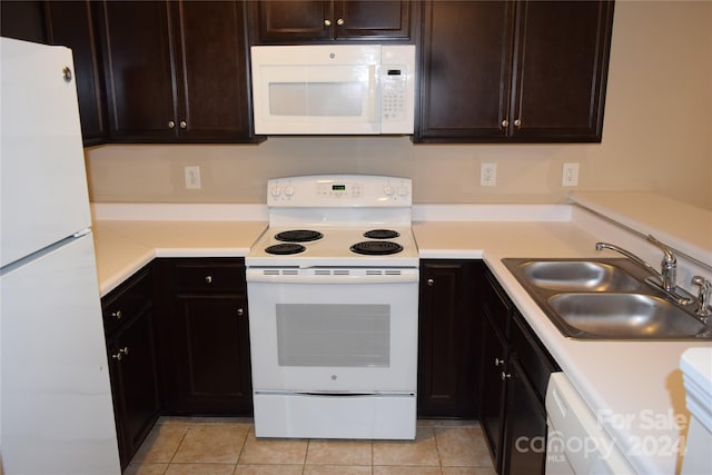 kitchen featuring dark brown cabinetry, white appliances, sink, and light tile patterned floors