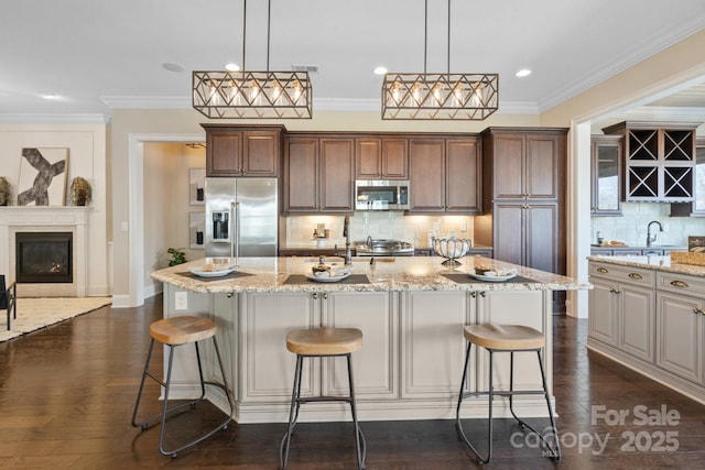 kitchen with decorative light fixtures, a breakfast bar, an island with sink, and appliances with stainless steel finishes