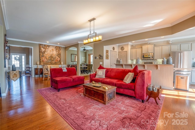 living room featuring ceiling fan, wood-type flooring, and ornamental molding