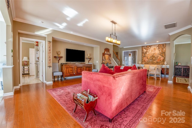 living room featuring an inviting chandelier, crown molding, and hardwood / wood-style floors