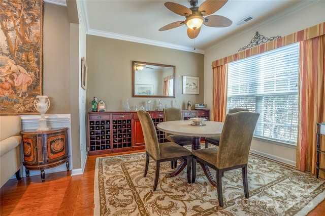 dining space featuring wood-type flooring, crown molding, and plenty of natural light