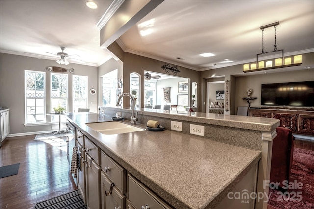 kitchen featuring an island with sink, dark hardwood / wood-style flooring, ornamental molding, pendant lighting, and sink