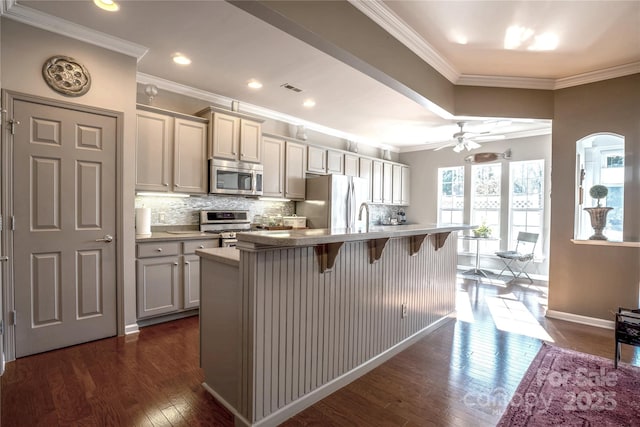 kitchen with tasteful backsplash, a center island with sink, a breakfast bar area, stainless steel appliances, and dark hardwood / wood-style flooring