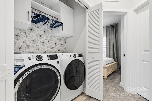 clothes washing area with light carpet, washer and dryer, and cabinets