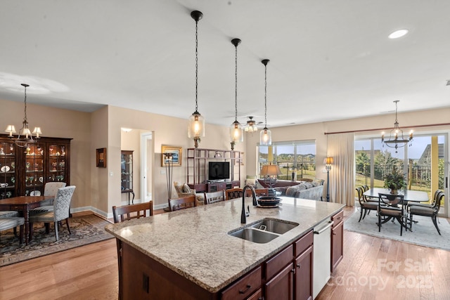 kitchen featuring pendant lighting, a notable chandelier, sink, and a center island with sink