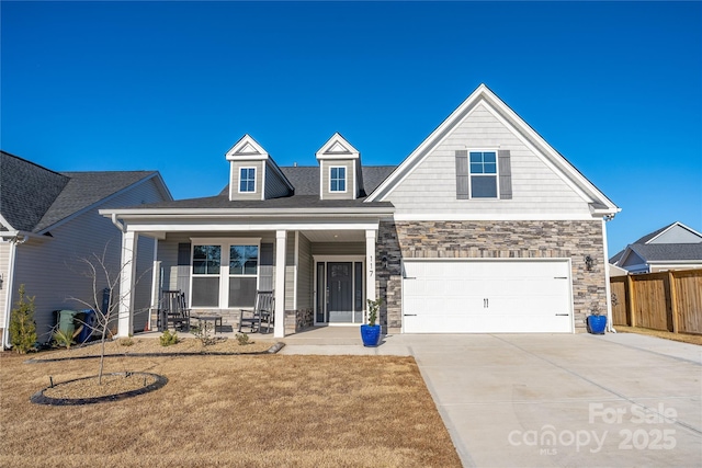 view of front of property featuring a garage, covered porch, and a front yard