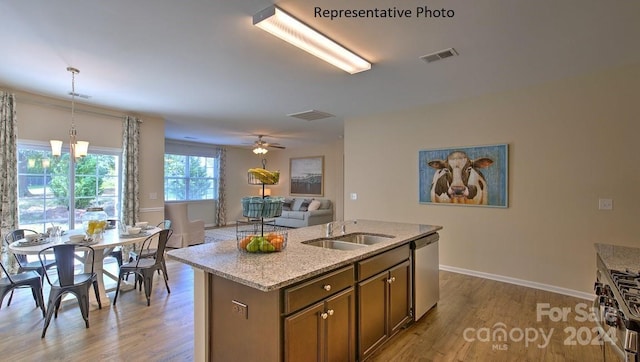 kitchen featuring light stone countertops, sink, stainless steel appliances, an island with sink, and pendant lighting