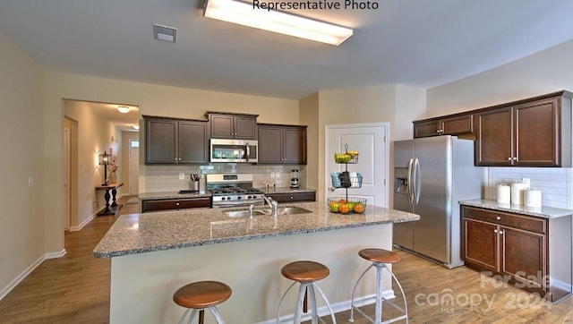 kitchen featuring a kitchen bar, light stone countertops, sink, and stainless steel appliances