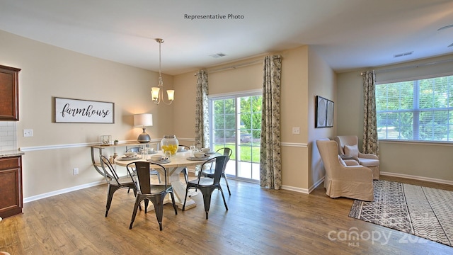 dining area featuring hardwood / wood-style floors, an inviting chandelier, and a healthy amount of sunlight