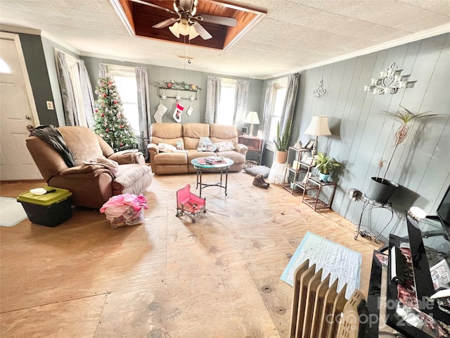 living room with ceiling fan, wooden walls, and ornamental molding