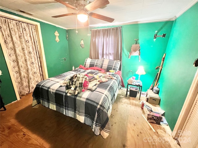 bedroom with hardwood / wood-style floors, ceiling fan, and ornamental molding