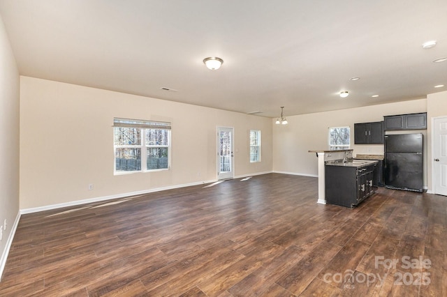 kitchen with freestanding refrigerator, open floor plan, dark cabinets, and dark wood finished floors