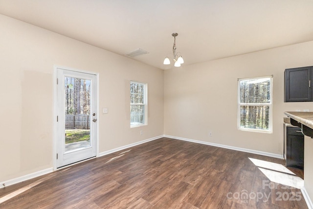 unfurnished dining area with dark wood-style flooring, baseboards, a chandelier, and visible vents