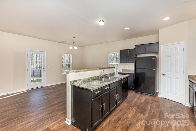 kitchen with dark wood finished floors, a sink, an island with sink, and freestanding refrigerator