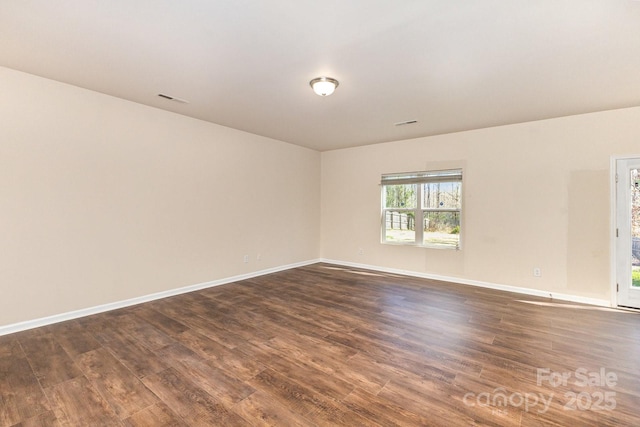 empty room featuring baseboards, visible vents, and dark wood-type flooring