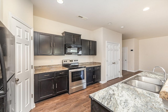kitchen with stainless steel range with electric stovetop, a sink, visible vents, black microwave, and wood finished floors
