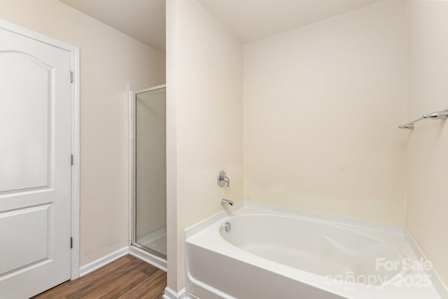 full bathroom featuring a shower stall, wood finished floors, and a bath