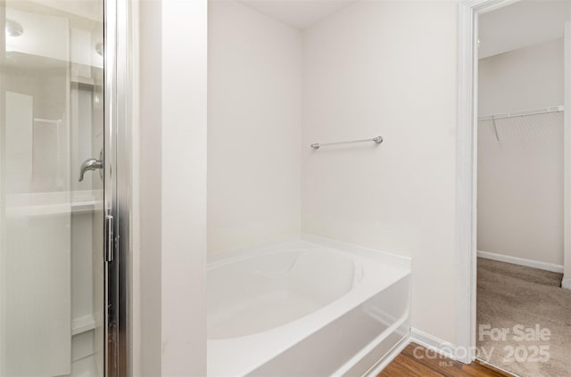 bathroom featuring a stall shower, a walk in closet, and a bath